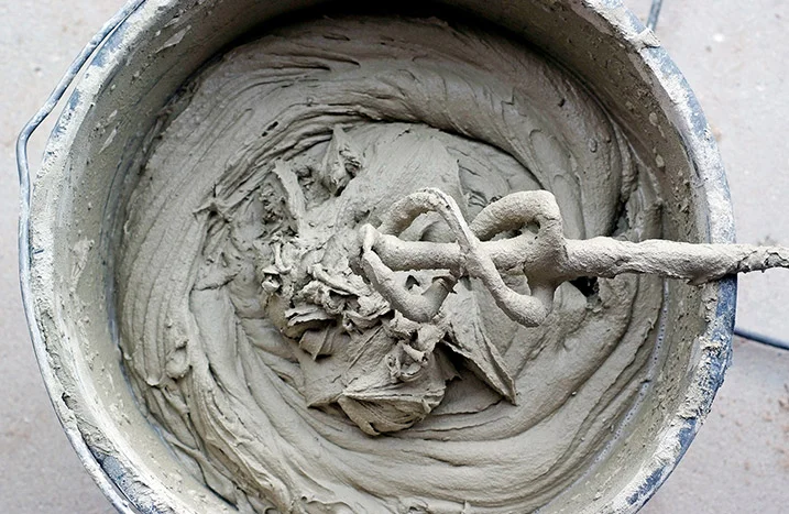 Mörtel wird in einem Eimer mit einem Rührwerk verrührt